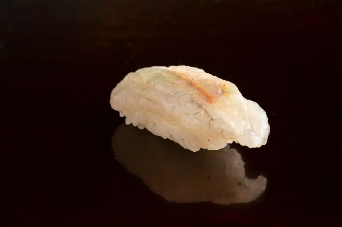 創作寿司の原点と言える、65年間握り続けてきた逸品。薄く開いた、ヒガンフグで小ねぎやもみじおろしを挟んである。邪道といわれたこの寿司も今や小倉の王道